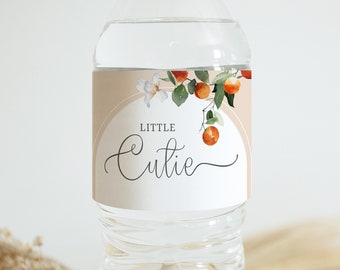 May include: Water bottle label with a peach background and a floral design featuring orange blossoms and oranges. The text "Little Cutie" is written in black cursive font.