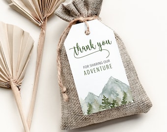 May include: A white thank you tag with green text that reads "thank you for sharing our adventure". The tag is attached to a small burlap bag with a watercolor illustration of mountains and trees.
