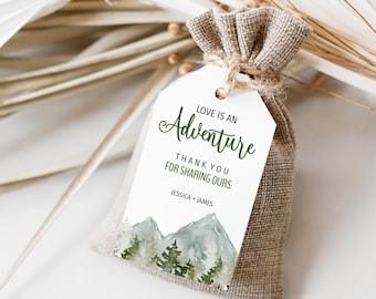 May include: White favor tag with green watercolor mountains and trees. The text reads "Love is an Adventure. Thank you for sharing ours. Jessica + James".