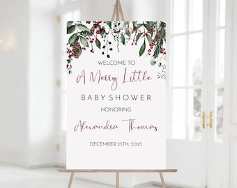 May include: A white welcome sign with a watercolor design of red berries and green leaves. The text reads "Welcome to A Merry Little Baby Shower Honoring Alexandra Thomas December 25th, 2025".
