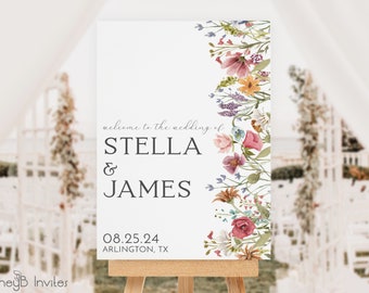 May include: A white wedding welcome sign on a wooden easel. The sign features the text "welcome to the wedding of STELLA & JAMES" and the date "08.25.24" with the location "ARLINGTON, TX". A floral border in shades of pink, orange, and purple decorates the right side.