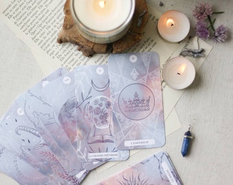 May include: A spread of tarot cards on a white surface with a lit candle and two tea lights. The cards are decorated with a watercolour background and have a geometric pattern. The cards are labelled with Roman numerals and the names of the cards, including "The Empress" and "The Sun".