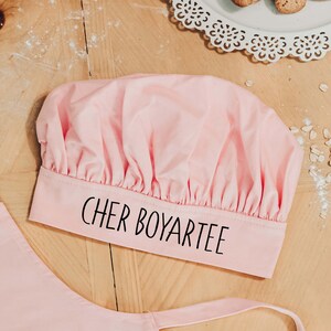 May include: Pink chef's hat with the text "Cher Boyartee" printed on the band.