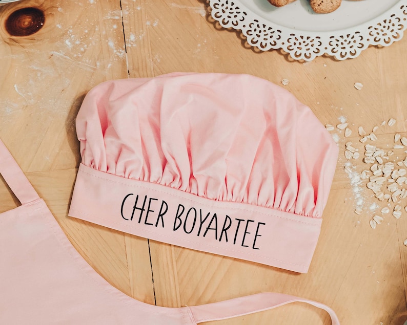 May include: Pink chef's hat with the text "Cher Boyartee" printed on the band.