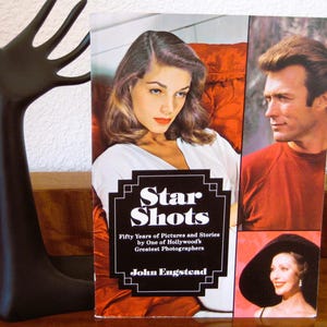 May include: A book titled "Star Shots" featuring images of Hollywood stars. The cover includes portraits of a woman in a white top, and a man in a red shirt. The book is by John Engstead.