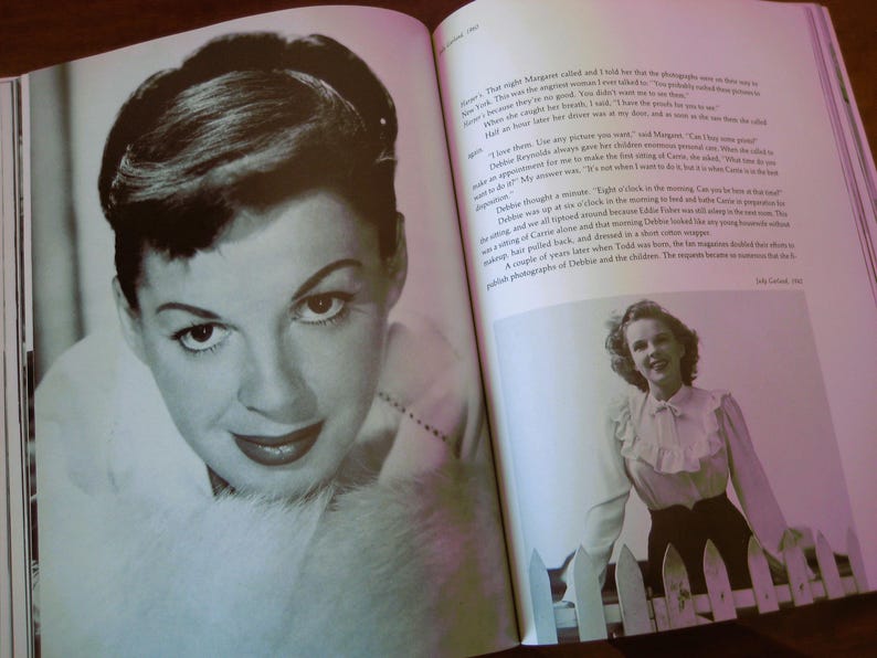 May include: A black and white photograph of a woman with dark hair and red lipstick, featured in a book. The image is a close-up of the woman's face, with a soft focus. The book is open, with text and another photograph visible.