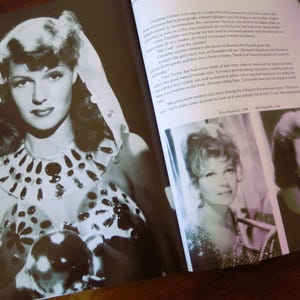 May include: Black and white photograph of a woman with dark hair and a head covering. She wears a decorative collar and a top with floral and dot patterns. The image is from a book.