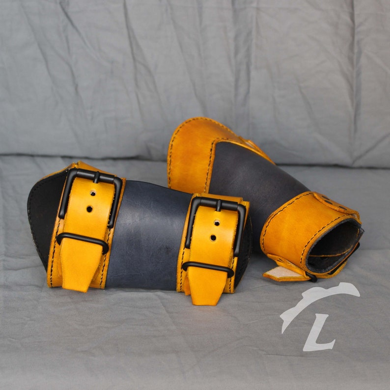 May include: Two leather wrist cuffs with adjustable buckles. One cuff is dark blue with yellow straps and the other is yellow with dark blue accents.