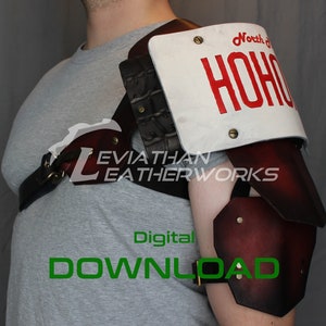 May include: A leather shoulder armour with a red and black colour scheme. The armour has a white plate with the text "North of HOHO" on it. The armour is worn by a person, but the person is not visible in the image.