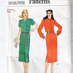 May include: A vintage Vogue Patterns sewing pattern showing two dress designs. One is a green dress with short sleeves, the other an orange dress with long sleeves. The pattern includes the text "Vogue Patterns" and the size "8".