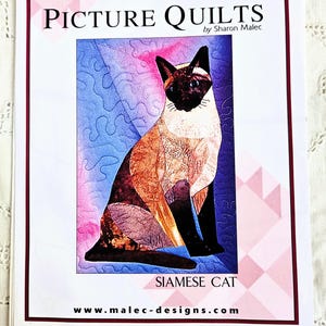 May include: A white instructional pattern booklet titled Picture Quilts by Sharon Malec featuring a Siamese cat illustration. The cover includes the Malec Designs logo, a red starburst graphic with text, and the website address at the bottom.