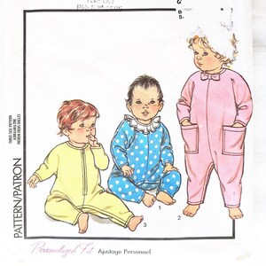 May include: A sewing pattern for three baby onesies. The onesies are in pink, blue with white polka dots, and yellow. The pattern is called "K's Fabric Chalet" and is for sizes 6 months, 12 months, and 18 months.