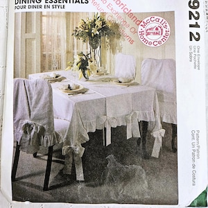 May include: A McCall's Home Decorating pattern envelope with a dining essentials design. The image shows a dining table set with a white tablecloth, chair covers, and decorative bows. The text "DINING ESSENTIALS" is visible.
