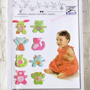 May include: A sewing pattern packet displaying several soft toy designs, such as bears and bunnies. The packet includes the Burda Creativ logo, the number 9637, and text in multiple languages. A baby in a red dress is also in the image.