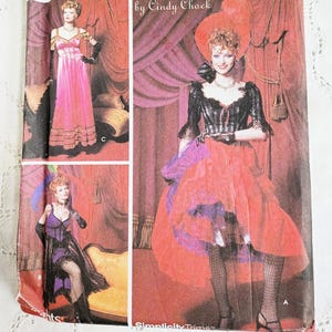 May include: A Simplicity Costumes sewing pattern envelope by Cindy Chock, size HH 6, 8, 10, 12. The front displays three costume variations: a pink gown, a purple corset outfit, and a black and red dress with a large hat, all featuring lace details.