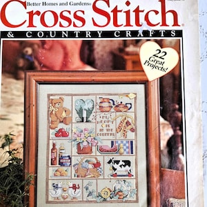 May include: A vintage "Better Homes and Gardens Cross Stitch & Country Crafts" magazine cover. The cover features a framed cross-stitch sampler with a teddy bear, hearts, flowers, and a cow. The magazine has a May/June 93 date and a "22 Great Projects!" sticker.