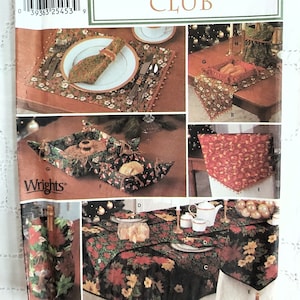 May include: A Simplicity Christmas Club sewing pattern with instructions for making a variety of festive items, including a table runner, placemats, a napkin ring, a chair cover, and a bread basket. The pattern is printed on a white background with red and green illustrations.