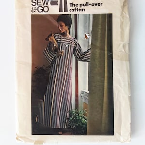 May include: A vintage sewing pattern for a pull-over caftan. The pattern is from Butterick, number 3916, and is for a size small. The pattern shows a woman wearing a striped caftan with a dog.