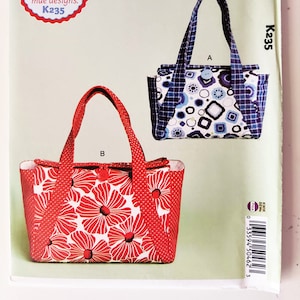 May include: A sewing pattern for two tote bags. The pattern is called "Perfect Totes" and is from ellie mae designs. The pattern number is K235. One tote bag is red with a floral print and the other is blue with a geometric print.