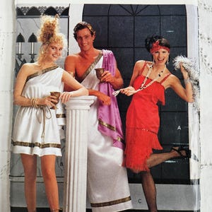 May include: Butterick 4199 sewing pattern envelope featuring three costume designs. One person wears a white one-shoulder tunic with gold trim, another a white toga with a purple drape, and the third a red fringed dress with a headband.