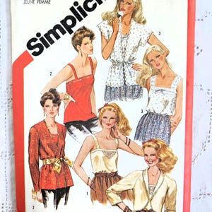 Peut inclure: Pochette de patron de couture Simplicity vintage avec des illustrations de hauts et de vestes pour femmes. La couverture est blanche avec un bord rouge et le logo Simplicity. Le numéro du patron est 5552.