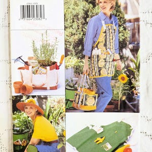 Peut inclure: Pochette de patron de couture Butterick 4364 illustrant un tablier de jardinage, un sac fourre-tout à outils et un chapeau de soleil. Les images présentent des tissus à motifs tournesols, du tissu vert uni et des matériaux en toile.