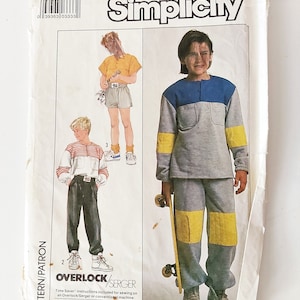 May include: A Simplicity sewing pattern envelope, number 5406, size 7, featuring illustrations of clothing sets including a grey sweatshirt with blue and yellow accents, grey trousers with yellow patches, and a white shirt with red stripes.
