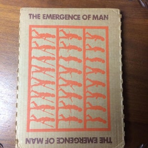 May include: A brown cardboard book cover with the title "THE EMERGENCE OF MAN" printed in brown letters. The cover features a series of orange silhouettes of stick figures in various stages of evolution.