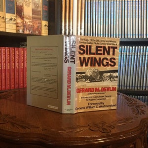 May include: A hardcover book titled "Silent Wings: The Saga of the U.S. Army and Marine Combat Glider Pilots During World War II" by Gerard M. Devlin. The book cover features a black and white photo of a glider in flight.