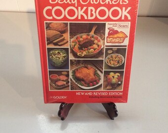 May include: A red hardcover cookbook titled "Betty Crocker's Cookbook" with a picture of an apple pie on the front cover. The cookbook is a new and revised edition, including microwave recipes. The cookbook is from Golden and is especially from Sears.