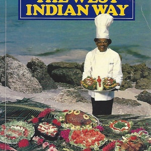 May include: A chef in a white uniform and hat stands on a beach holding a platter of food. The platter is filled with a variety of colorful fruits and vegetables. The chef is smiling and looking at the camera. The beach is sandy and there are palm trees in the background. The text "Cooking the West Indian Way" is displayed on a blue sign above the chef.