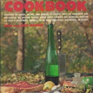 May include: A book cover with the title "The Complete Outdoor Cookbook" in red letters. The cover features a green wine bottle, a knife, and a variety of food items, including a steak, fish, lemons, and eggs. The text on the cover reads: "Hundreds of menus, recipes, and dozens of helpful hints on equipment and procedures. All anyone should know about cooking out of doors, whether the spot is apartment, terrace, patio, backyard, boat, wilderness, or desert. Dan and Inez Morris."