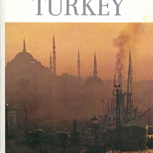 May include: A vintage book cover with the title "TURKEY" in large, bold, gray letters. The cover is white with a faded image of a cityscape at sunset with a ship in the harbor.