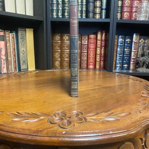 May include: A brown leather-bound book titled "Plutarch" with gold lettering. The book is part of a series called "The Great Books" and is numbered 17.