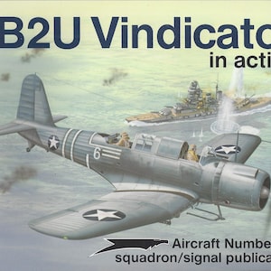 May include: Illustration of an SB2U Vindicator aircraft in action, with a battleship in the background. The aircraft is gray with white stars and the number 6. Text reads "SB2U Vindicator in action" and "Aircraft Number 122".