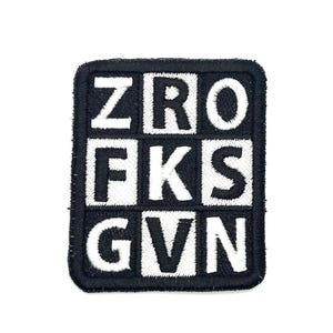May include: Black and white embroidered patch with the letters ZRO, FKS, and GVN arranged in a grid. The patch has a square shape with rounded corners and a black border. The letters are in a bold, sans-serif font.