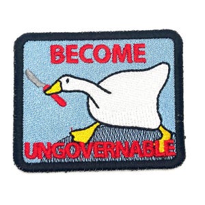 May include: Embroidered patch featuring a white goose with a knife, yellow feet, and a black outline. The patch has the words "BECOME UNGOVERNABLE" in red letters on a light blue background, framed by a dark blue border.