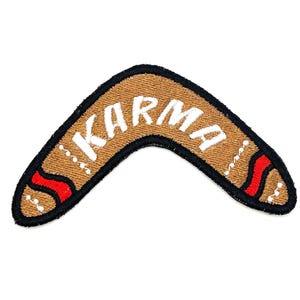 May include: A brown boomerang with red and white accents and the word "KARMA" written in white on the top.
