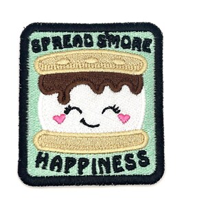 May include: Square embroidered patch featuring a smiling s'more with the text "SPREAD SMORE HAPPINESS". The s'more has a white marshmallow, chocolate, and graham crackers. The patch has a black border and a light green background.