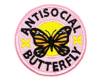 May include: Pink round embroidered patch with the text "Antisocial Butterfly" in black lettering. A yellow circle with a black and orange butterfly is in the center of the patch.