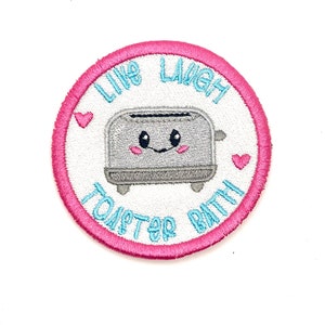 May include: A pink and white embroidered patch with a cartoon toaster and the text "Like Laugh Toaster Bath".
