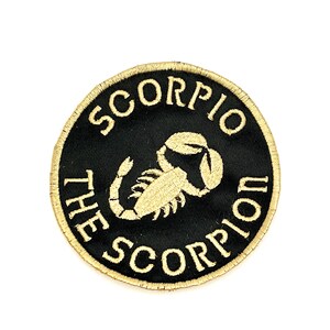 May include: A black and gold embroidered patch with the text "Scorpio The Scorpion" and a scorpion design.