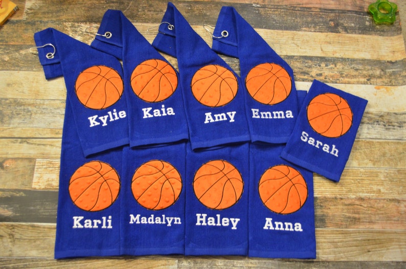 May include: Eight blue towels with orange basketballs and white embroidered names: Kylie, Kaia, Amy, Emma, Sarah, Karli, Madalyn, Haley, and Anna.