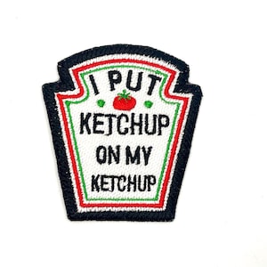 May include: A white and red embroidered patch with black trim shaped like a ketchup bottle. The patch says "I put ketchup on my ketchup".