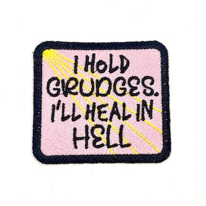 May include: Pink and black embroidered patch with yellow stitching. The patch reads "I hold grudges. I'll heal in hell."