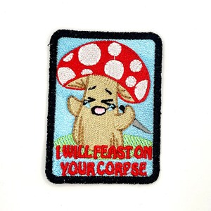 May include: A red and white mushroom with a smiling face holding a knife. The mushroom is wearing a brown outfit and the text "I WILL FEAST ON YOUR CORPSE" is below the mushroom.