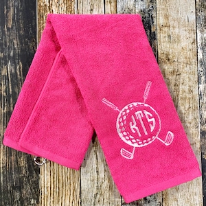 May include: Pink golf towel with a white embroidered golf ball and golf clubs with the monogram "RTS" in the center.