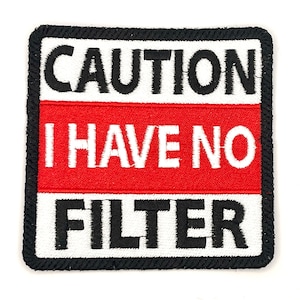 May include: A black and white embroidered patch with red accents. The patch reads "CAUTION I HAVE NO FILTER".