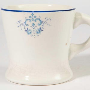 Puede incluir: Taza de cerámica blanca con borde y asa azules. Presenta un diseño floral azul. La taza tiene una forma ligeramente acampanada y un asa cómoda. Ideal para bebidas calientes.