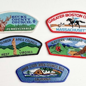 May include: Five embroidered scout patches featuring regional council names and locations: Bucks County Council Pennsylvania, Greater Boston Council Massachusetts, Mountaineer Area Council West Virginia, Eastern Arkansas Council, and Santa Lucia Area Council BSA California.